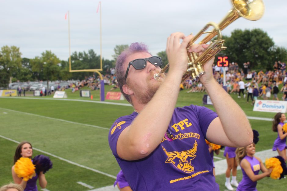 student trumpet player with purple hair outdoors at a ball game